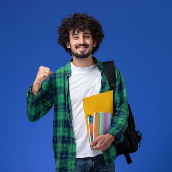 front-view-male-student-wearing-black-backpack-holding-copybooks-files-blue-wall - Copy